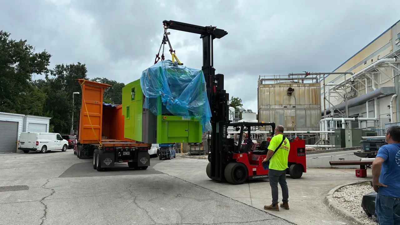 An Accuwright Versa-Lift unloading a machine from a trailer