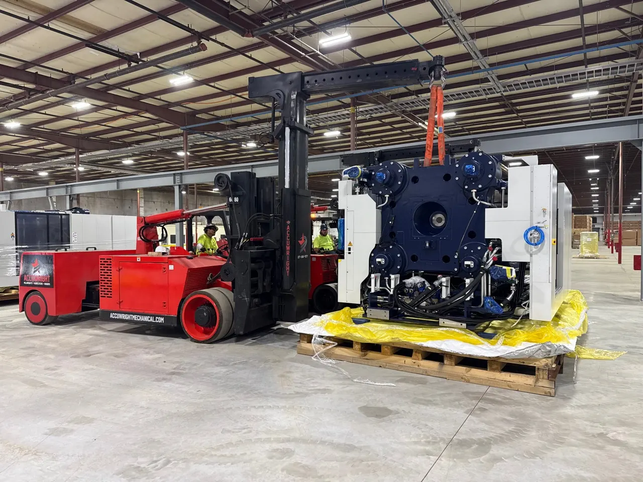 Two branded Accuwright forklifts positioning a large machine in a clean production plant