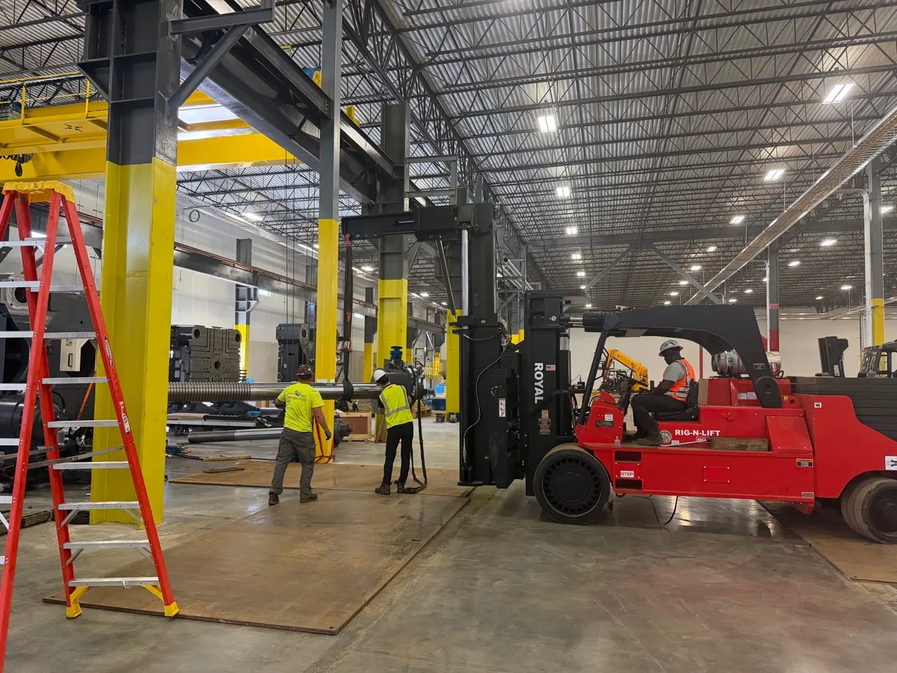 An Accuwright crew and RIG-N-LIFT operator guiding a machine shaft into position inside a plant
