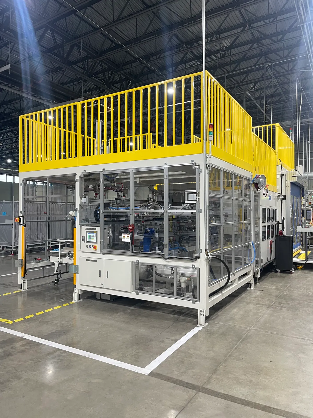 A completed automated production cell with clear guarding and a yellow upper platform