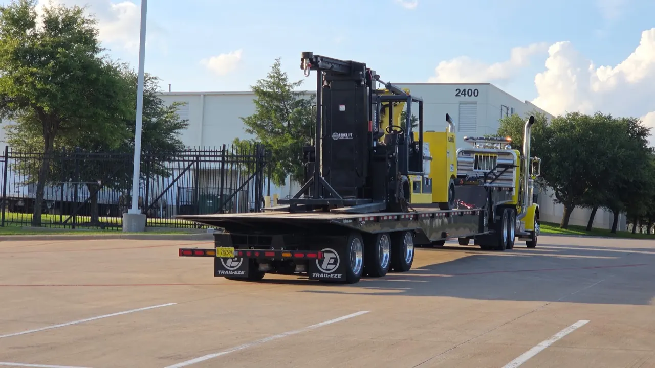 An Accuwright heavy forklift loaded on a tractor and lowboy trailer, mobilized for a job