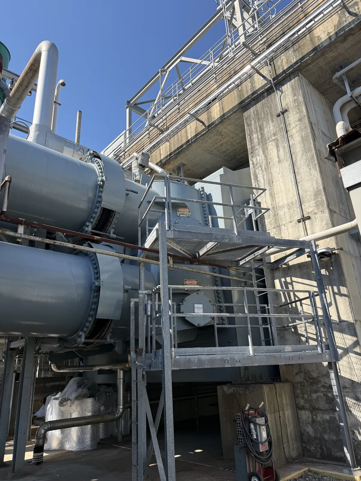 Large gray process equipment, ducts and access platforms outside an industrial structure