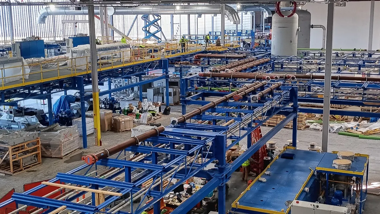 A wide completed industrial process line with blue structural steel, piping and mezzanine platforms