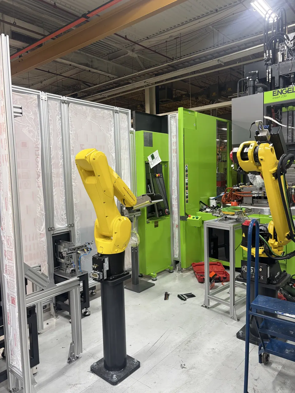 A bright green ENGEL insert 230 machine with two yellow robots during automation integration