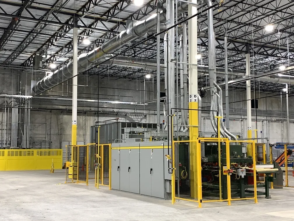 A completed industrial machine line with guarding, controls, ductwork and overhead utilities in a clean plant