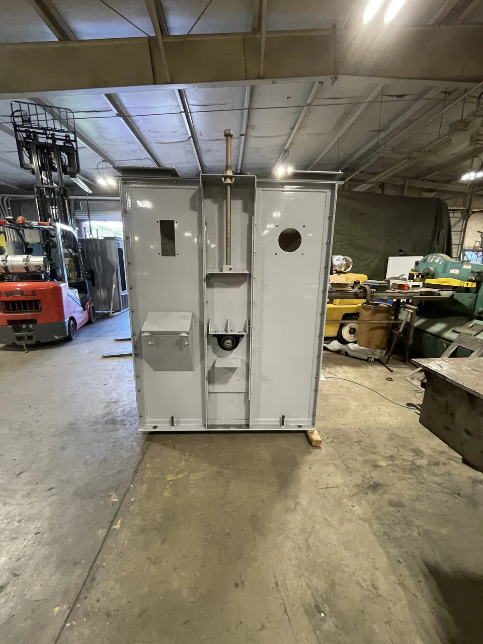 A newly fabricated gray bucket-elevator housing standing in the Accuwright fabrication shop