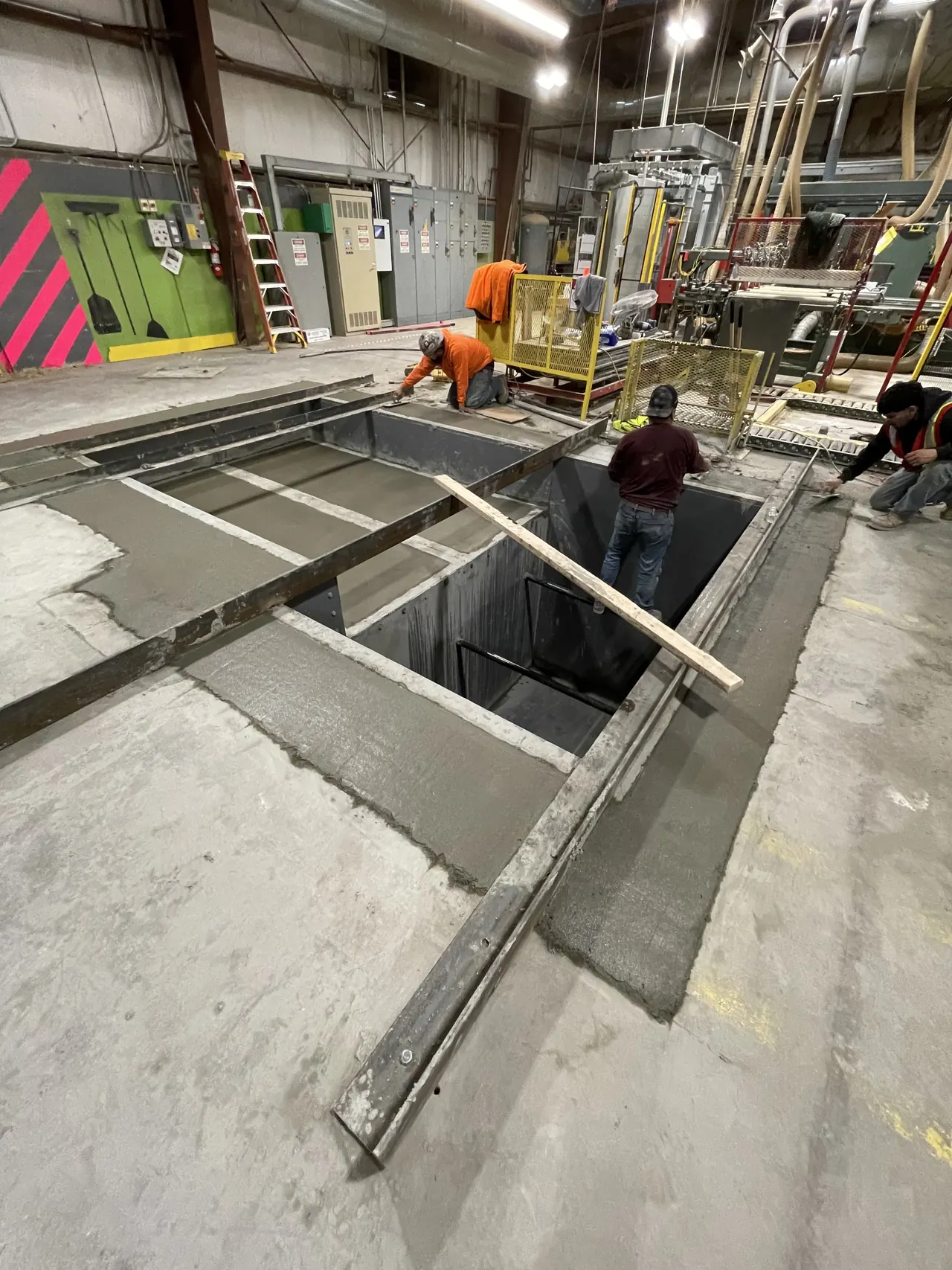 An Accuwright crew finishing concrete around a steel-framed equipment pit inside a plant