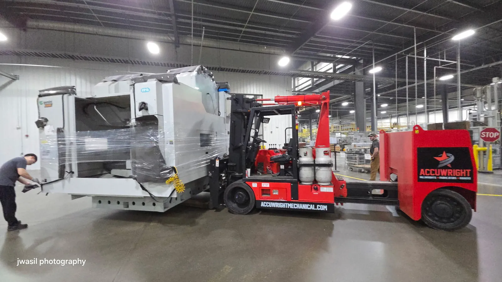 An Accuwright machinery mover carrying a wrapped CNC machine across a plant floor