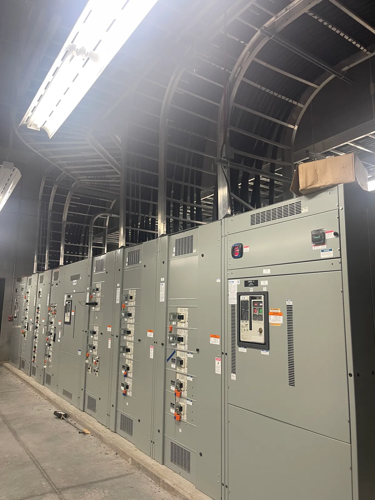 A switchgear and motor control lineup with cable trays arcing overhead into the gear