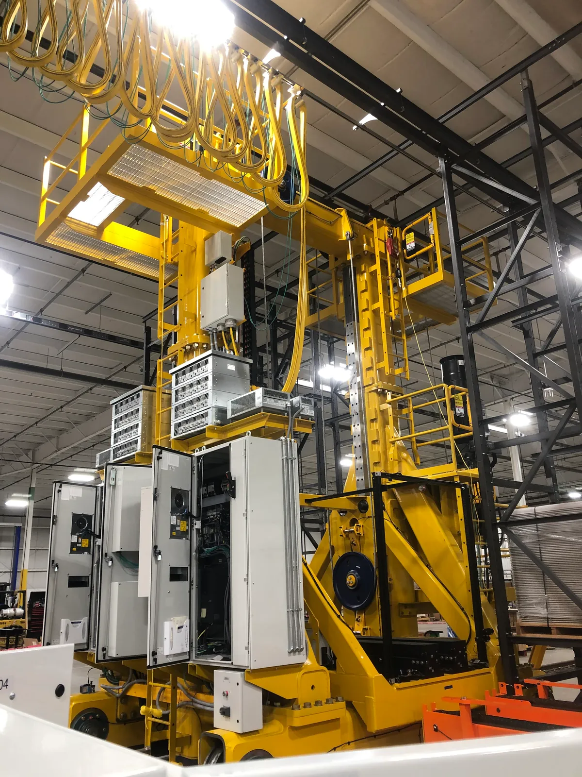 Open control cabinets mid-wire on a large production machine with festooned cable runs overhead